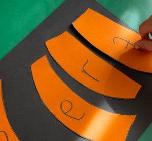 the letters e r and t on orange against a black backgrfound. the letter t is upside down.