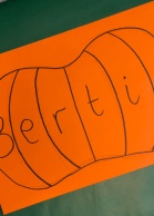 a pumpkin outline drawn on orange paper with the name Bertie written across it