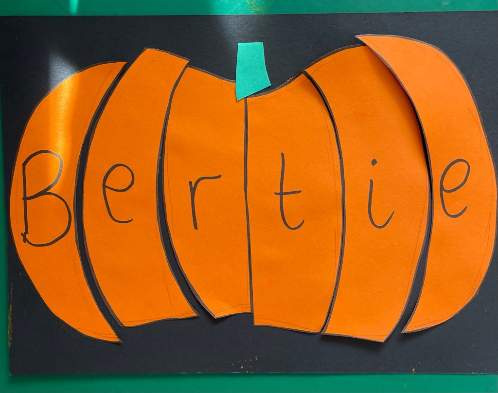 an orange pumpkin against a black background reads "Bertie" across the middle