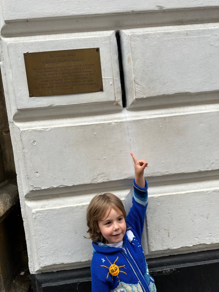 a boy is pointing upwards to the smallest window in britain located in hull