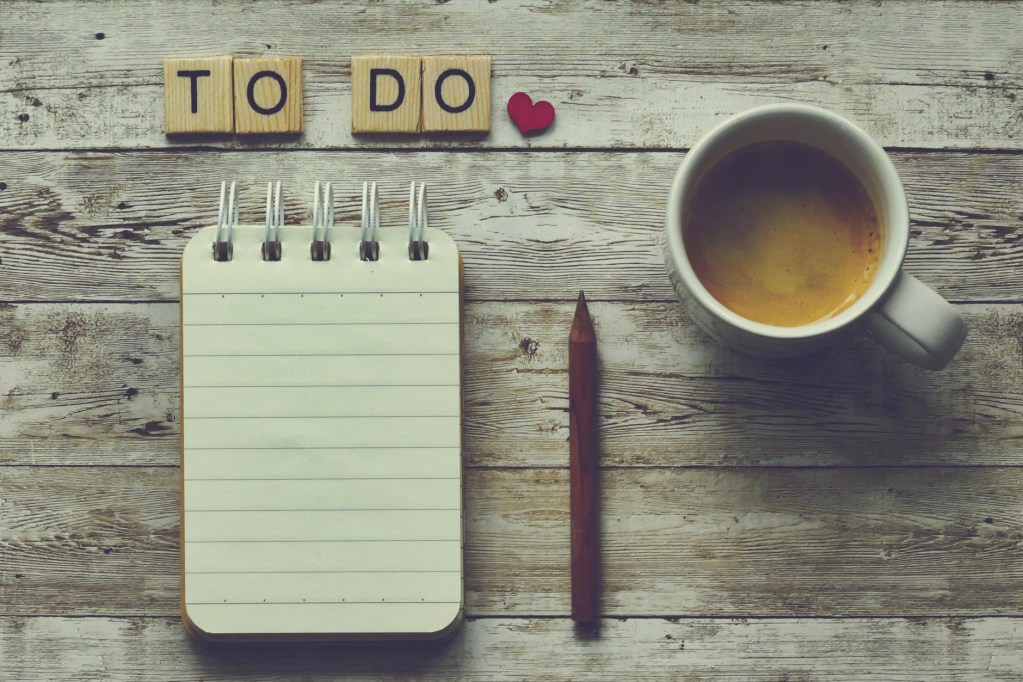blank notepad and pencil with a cup of cofee. scrabble tiles above say "to do"